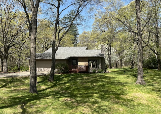 view of front facade featuring a garage, driveway, a chimney, a deck, and a front lawn
