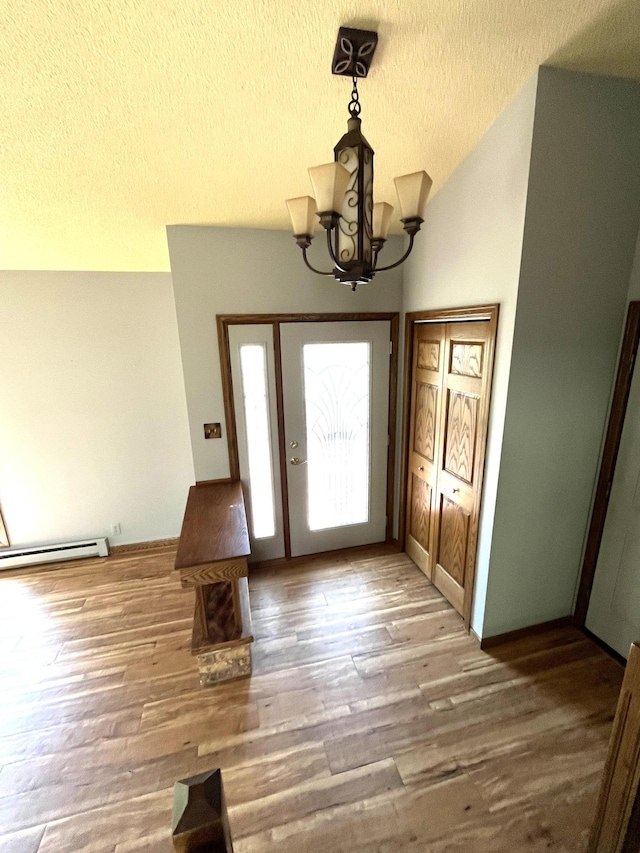 entryway with a baseboard heating unit, a textured ceiling, a chandelier, wood finished floors, and lofted ceiling