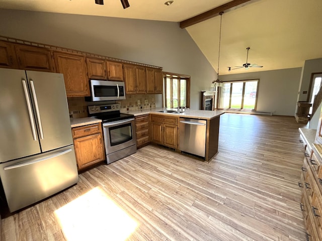 kitchen featuring stainless steel appliances, a ceiling fan, a sink, light countertops, and beamed ceiling