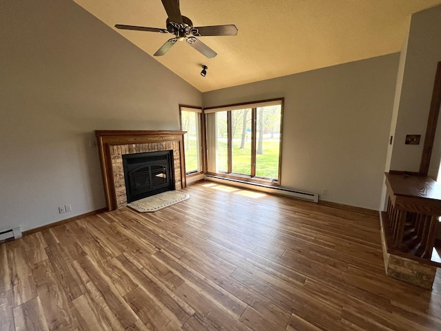 unfurnished living room with a baseboard radiator, wood finished floors, a glass covered fireplace, ceiling fan, and high vaulted ceiling