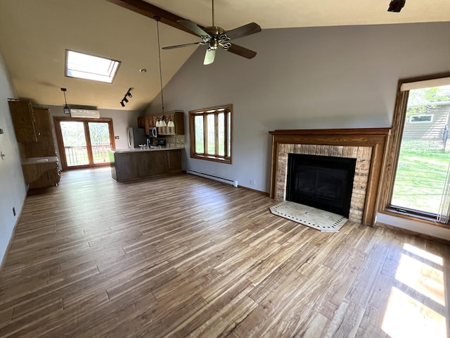 unfurnished living room with a fireplace, a ceiling fan, wood finished floors, and high vaulted ceiling