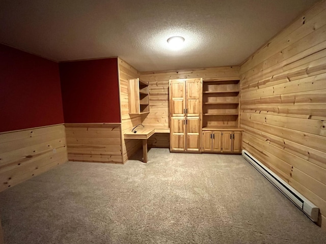 unfurnished office featuring wooden walls, a baseboard radiator, light colored carpet, and a textured ceiling