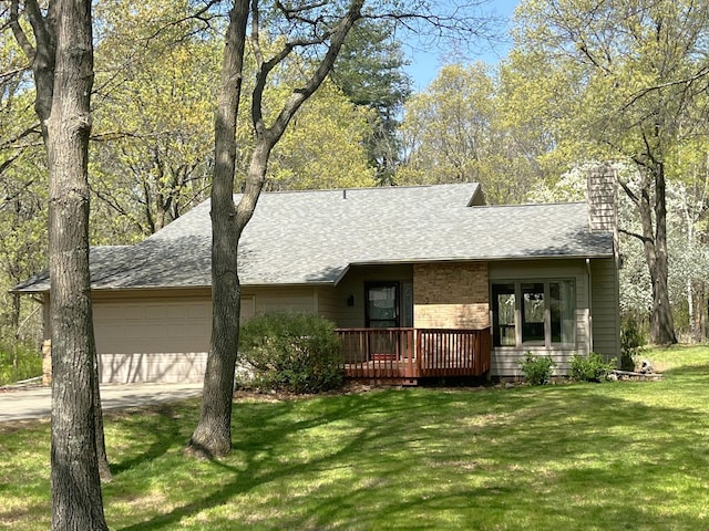 view of front of house featuring an attached garage, a chimney, concrete driveway, a front lawn, and a shingled roof