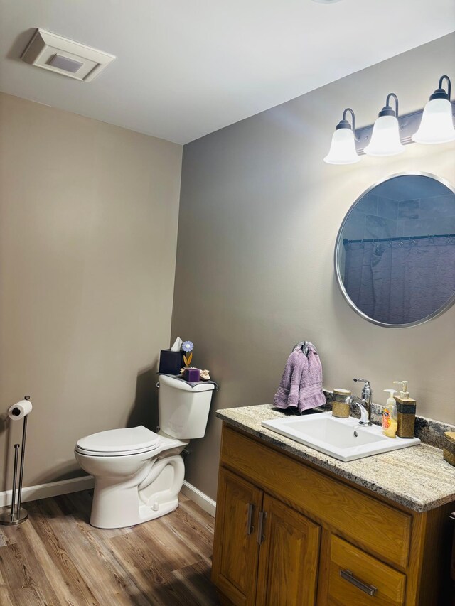 1008 Ruby St NW, Alexandria, MN 56308 - bathroom featuring wood finished floors, baseboards, toilet, and vanity