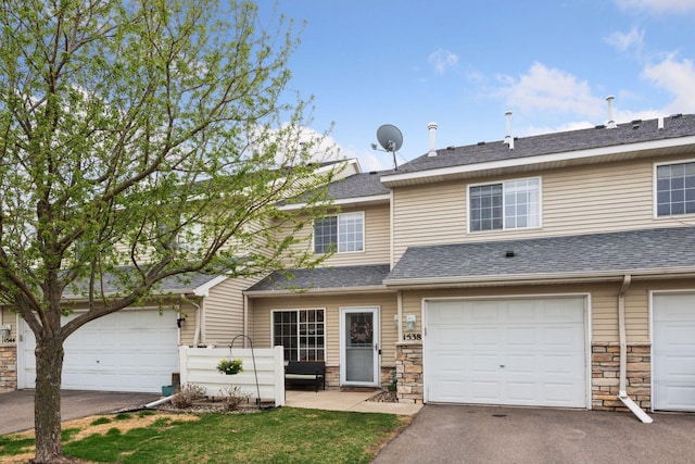 traditional home with an attached garage, driveway, a shingled roof, and stone siding