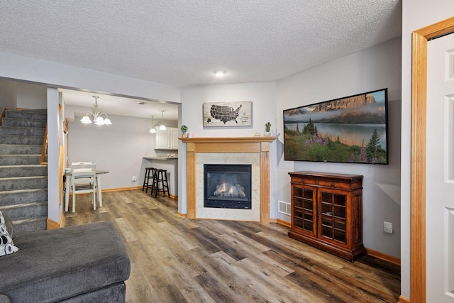 living room featuring stairway, a textured ceiling, baseboards, and wood finished floors