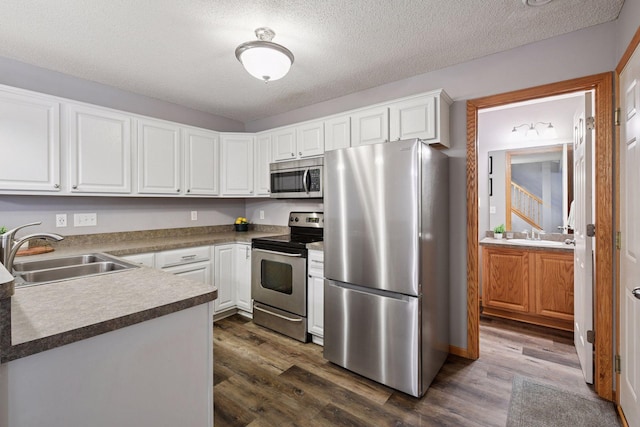 kitchen with a sink, white cabinets, stainless steel appliances, and dark wood-type flooring