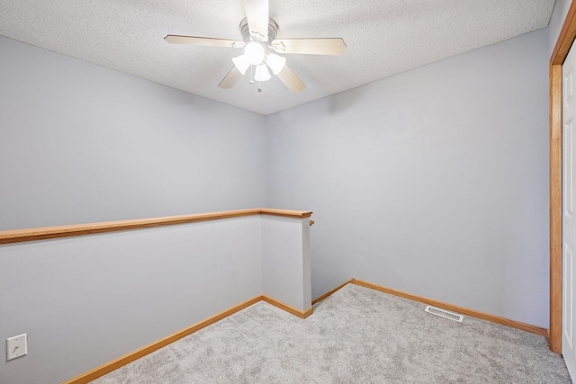 unfurnished room with carpet flooring, a textured ceiling, visible vents, and ceiling fan