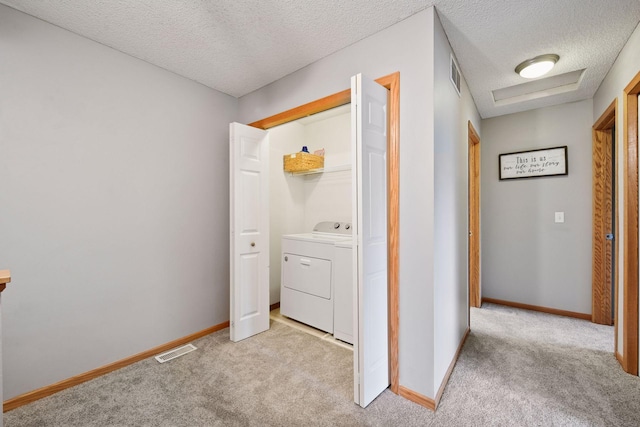 clothes washing area featuring a textured ceiling, laundry area, visible vents, and light carpet
