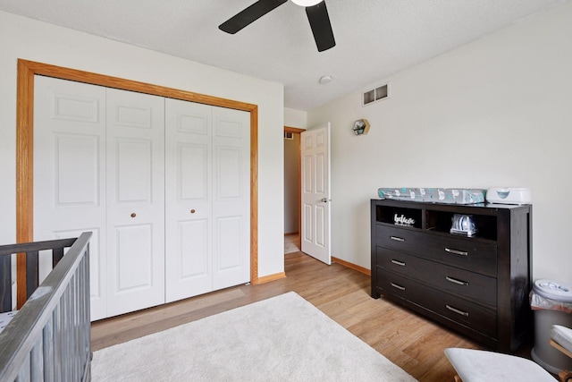 bedroom with light wood finished floors, a ceiling fan, baseboards, visible vents, and a closet