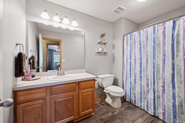 full bath with a textured ceiling, visible vents, wood finished floors, vanity, and toilet