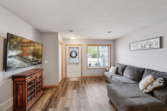 living room with a textured ceiling, baseboards, wood finished floors, and visible vents