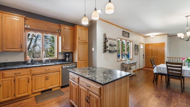 kitchen featuring wood finished floors, stainless steel dishwasher, hanging light fixtures, a sink, and a notable chandelier