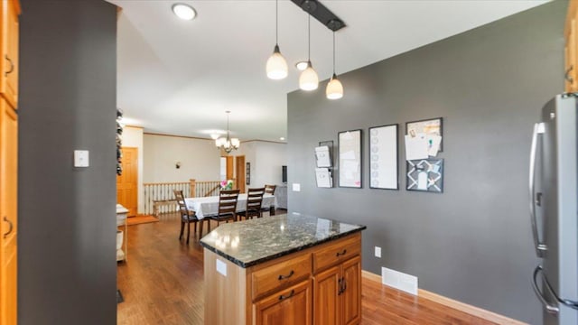kitchen featuring dark wood-style floors, a chandelier, dark stone countertops, visible vents, and freestanding refrigerator