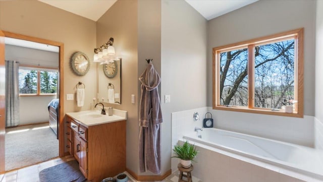 ensuite bathroom with connected bathroom, a bath, and vanity