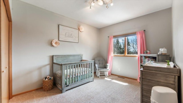 bedroom featuring a crib, carpet flooring, visible vents, and baseboards