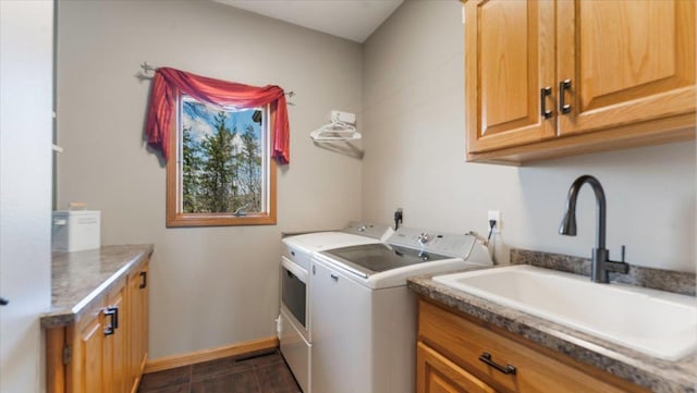 washroom with baseboards, a sink, cabinet space, and independent washer and dryer
