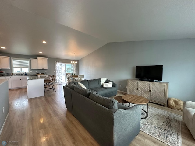 6054 59th St S, Fargo, ND 58104 - living area featuring an inviting chandelier, baseboards, light wood-style floors, and vaulted ceiling