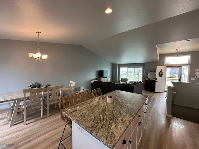 6054 59th St S, Fargo, ND 58104 - kitchen with white cabinets, a breakfast bar area, light wood-style flooring, dark stone counters, and lofted ceiling
