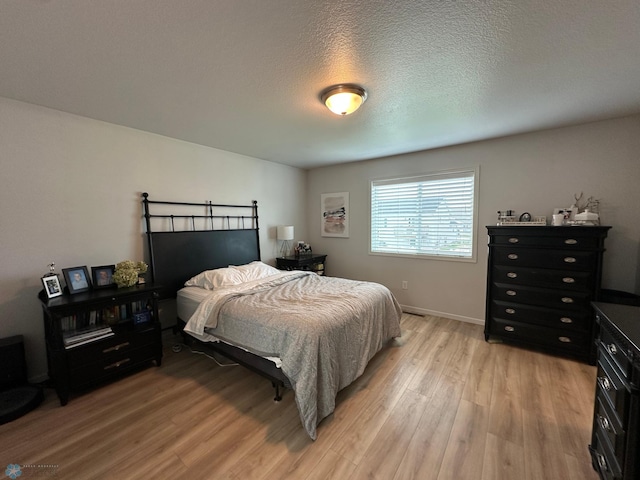 6054 59th St S, Fargo, ND 58104 - bedroom with light wood-style floors, a textured ceiling, and baseboards
