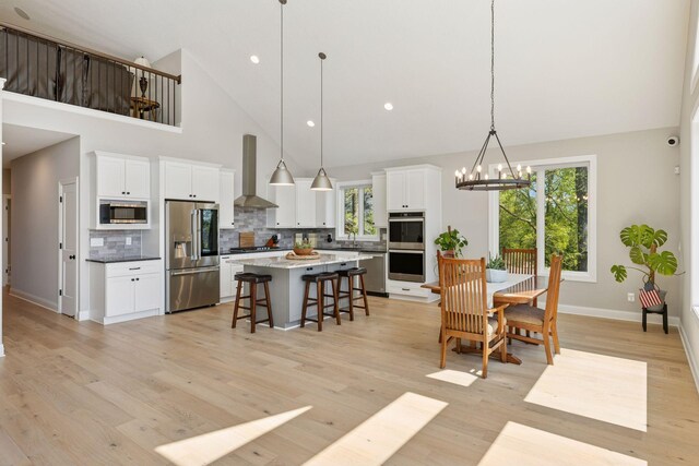 1929 Fagerness Point Rd, Orono, MN 55391 - dining room with high vaulted ceiling, a chandelier, baseboards, light wood finished floors, and recessed lighting