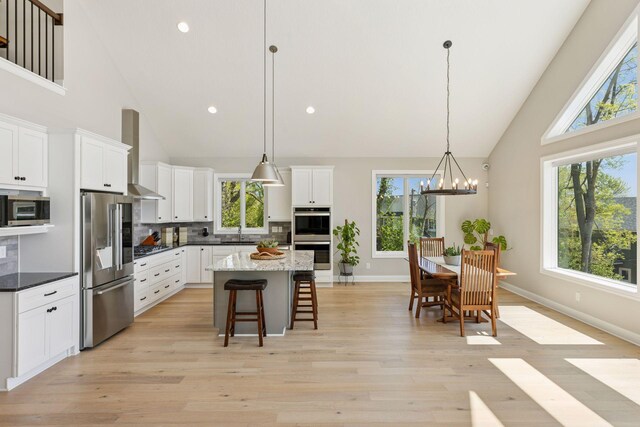 1929 Fagerness Point Rd, Orono, MN 55391 - kitchen with appliances with stainless steel finishes, high vaulted ceiling, wall chimney exhaust hood, a sink, and healthy amount of natural light