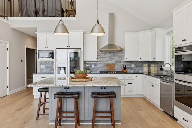 1929 Fagerness Point Rd, Orono, MN 55391 - kitchen featuring appliances with stainless steel finishes, wall chimney range hood, a sink, tasteful backsplash, and light wood-style floors