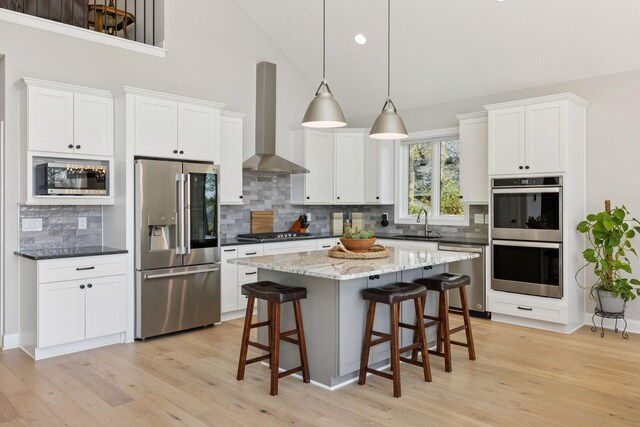 1929 Fagerness Point Rd, Orono, MN 55391 - kitchen featuring stainless steel appliances, wall chimney exhaust hood, backsplash, light wood-type flooring, and high vaulted ceiling