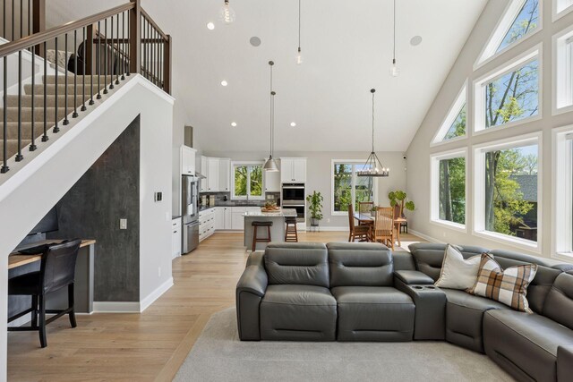 1929 Fagerness Point Rd, Orono, MN 55391 - living area with high vaulted ceiling, light wood-style floors, baseboards, a chandelier, and stairway