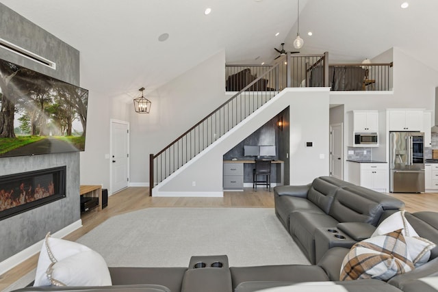 1929 Fagerness Point Rd, Orono, MN 55391 - living area with light wood-type flooring, high vaulted ceiling, stairs, a fireplace, and baseboards