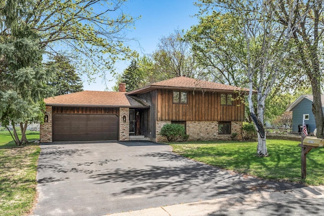 tri-level home with driveway, brick siding, an attached garage, and a front yard