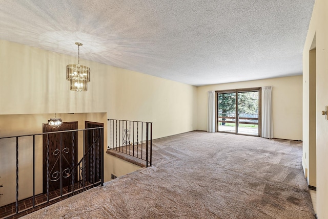 unfurnished room featuring a chandelier, a textured ceiling, and carpet
