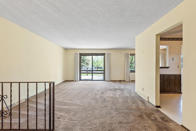 unfurnished room with a textured ceiling, carpet, and visible vents
