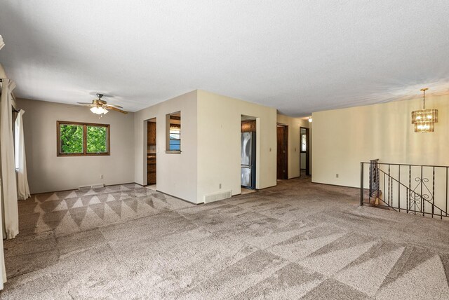 empty room featuring carpet flooring, ceiling fan with notable chandelier, and visible vents