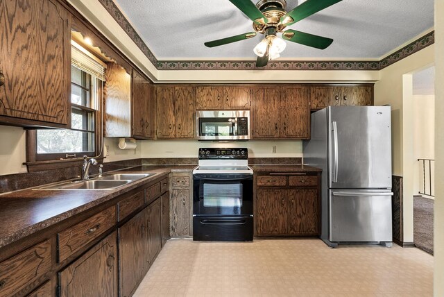 kitchen with light floors, dark countertops, stainless steel appliances, and a sink