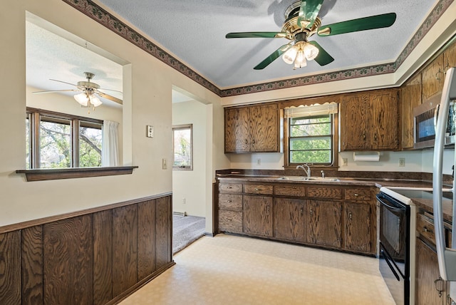 kitchen featuring a ceiling fan, a sink, dark countertops, black range with electric stovetop, and a textured ceiling