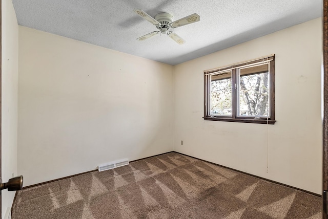 carpeted spare room featuring ceiling fan, a textured ceiling, and visible vents