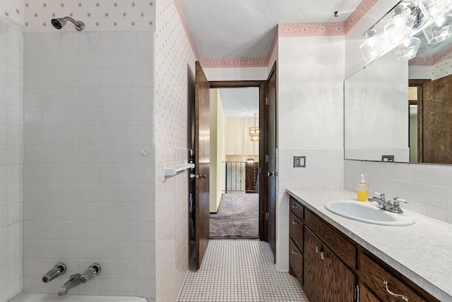 full bath with tile walls, wallpapered walls, walk in shower, a washtub, and vanity