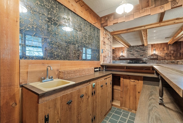 kitchen featuring a sink, wallpapered walls, and brown cabinets