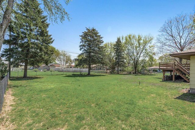 view of yard with fence, a wooden deck, and stairs