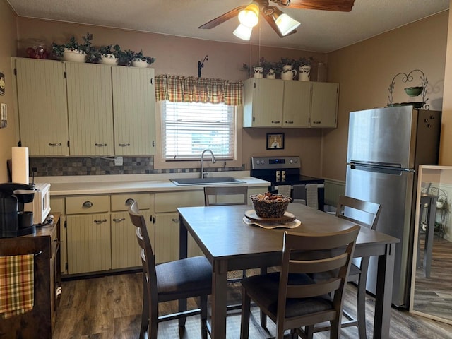 kitchen featuring cream cabinets, appliances with stainless steel finishes, a sink, light wood-type flooring, and a ceiling fan