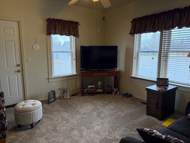 living room featuring a ceiling fan, carpet flooring, baseboards, and a healthy amount of sunlight