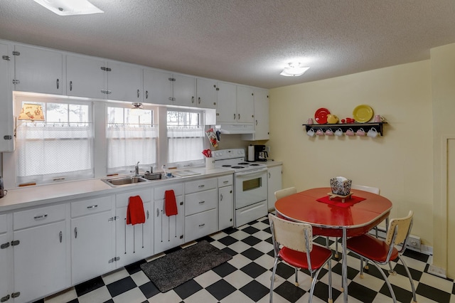kitchen with white electric range oven, tile patterned floors, under cabinet range hood, plenty of natural light, and a textured ceiling
