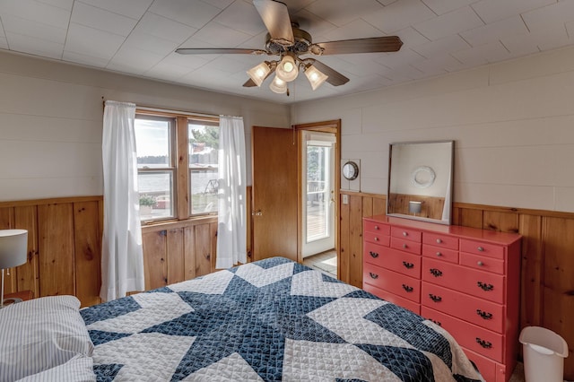 bedroom featuring wooden walls and a ceiling fan