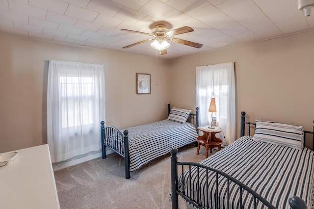 bedroom with multiple windows, light colored carpet, and a ceiling fan