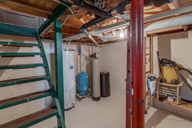 unfinished basement with electric water heater, a water pressure tank, a water softener, and stairs
