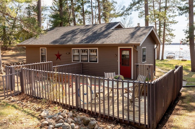 chalet / cabin featuring roof with shingles and a deck with water view