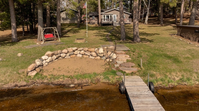 view of green lawn featuring a boat dock and a wooden deck