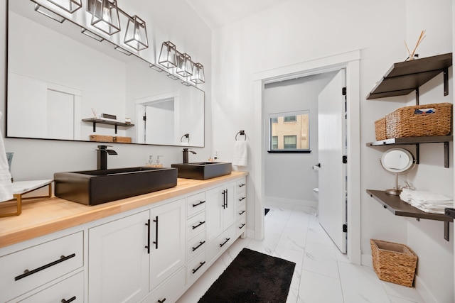 full bathroom featuring baseboards, a sink, and marble finish floor