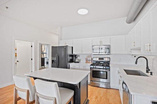 kitchen with backsplash, stainless steel appliances, a kitchen breakfast bar, and a sink
